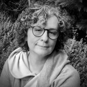 A portrait photo of Joanna Apanowicz, a brunette with curly hair wearing glasses