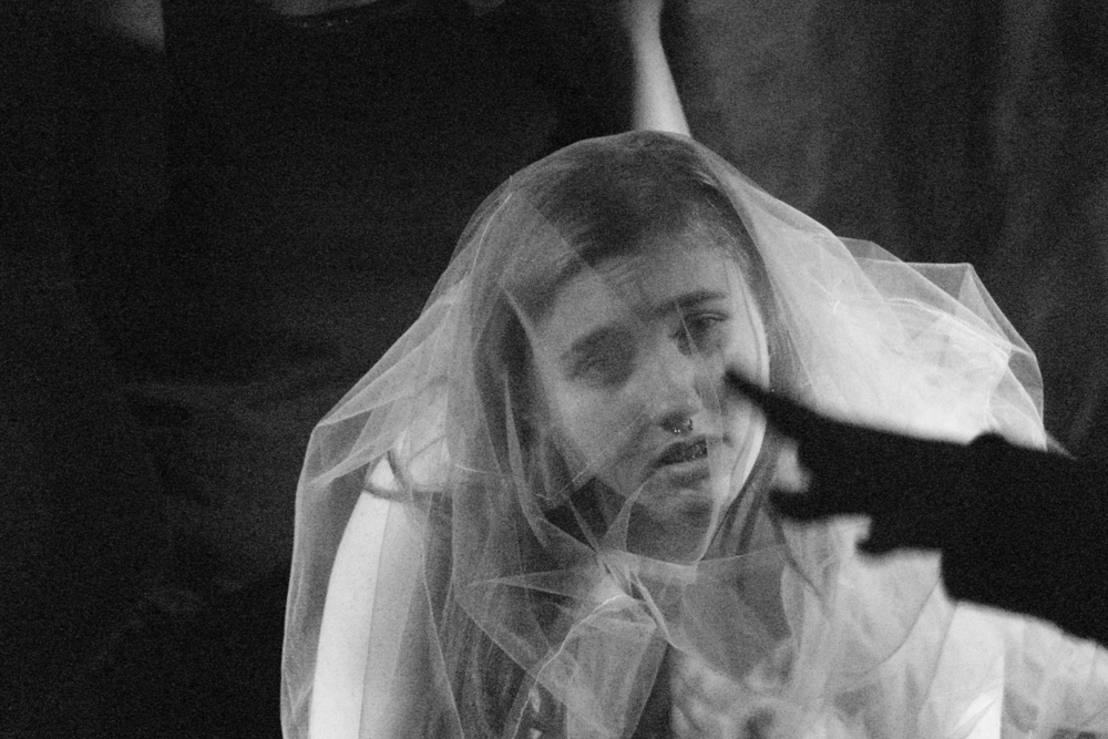 A still from the performance, a black and white photograph, a woman in a wedding dress looking straight ahead A still from the performance, a black and white photograph, a woman in a wedding dress looking straight ahead