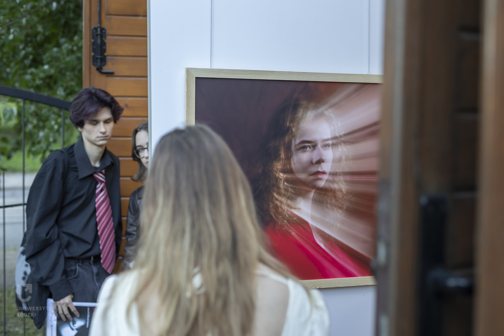 Weronika's portrait exhibited at the Wozownia Gallery; people watching the photographs around