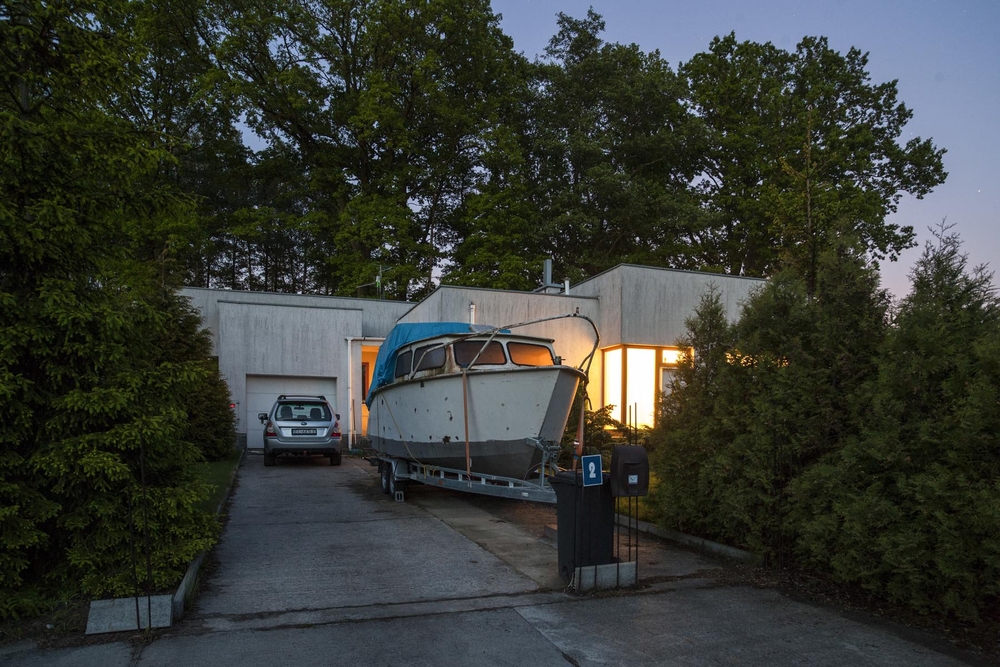 A photo by Artur Urbański, which shows a boat and a house in the evening