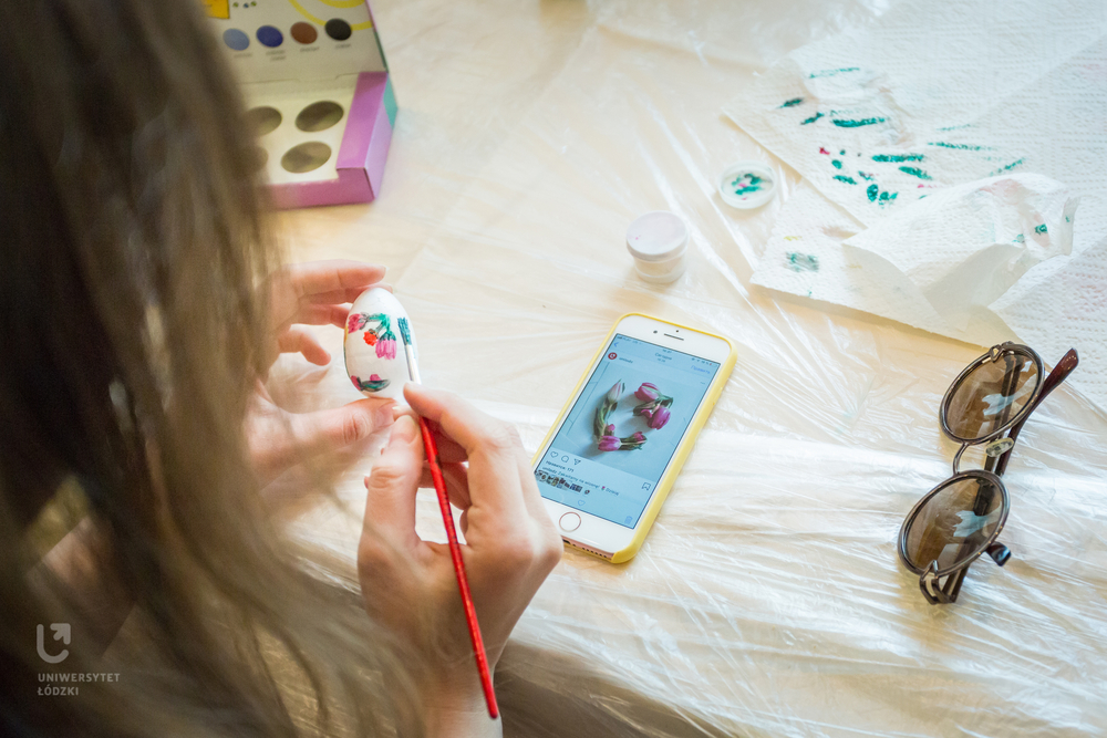 A woman with long hair painting an Easter egg